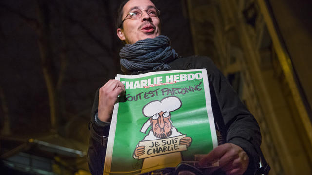 A Parisian man speaks to a TV reporter after buying a copy of the latest edition of Charlie Hebdo 