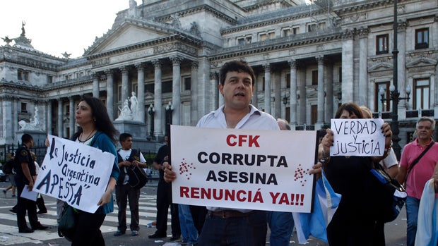 A man holds a sign that reads, "CFK (Argentina's President Cristina Fernandez de Kirchner) corrupt, murderer, resign now!" during a demonstration outside Argentina's congress in Buenos Aires Feb. 4, 2015. 