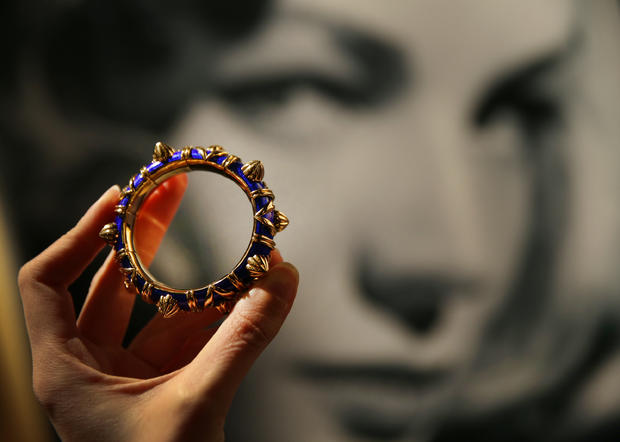 An enamel and 18-karat gold bracelet belonging to Lauren Bacall are displayed in front of a photograph of the actress at Bonhams auctioneers in London, England, Feb. 13, 2015. 