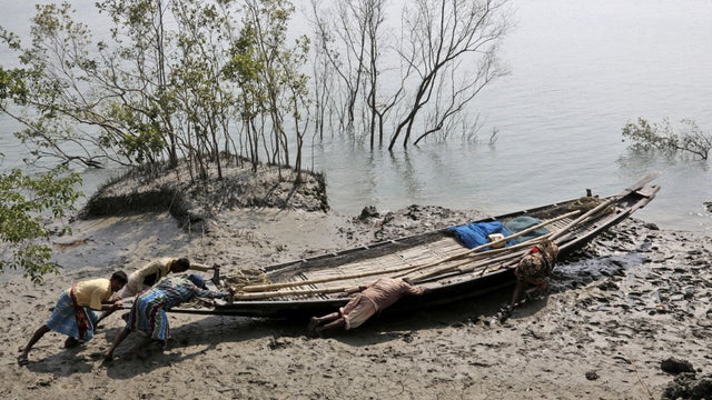 Villagers help a couple push their fishing boat to the water at Satyanarayanpur village in the Sundarbans 