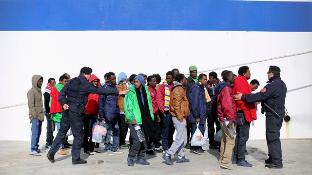 Italian Carabiniere give instructions to migrants as they are transferred to another immigration center by a ferry on the southern Italian island of Lampedusa 
