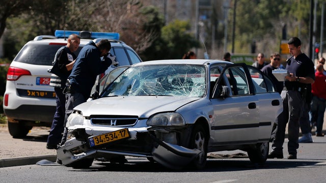 Israeli policemen inspect the car used by a Palestinian motorist to ram into a group of pedestrians in Jerusalem 