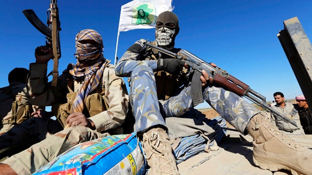 Masked Shi'ite fighters hold their weapons in Al Hadidiya, south of Tikrit, en route to the ISIS-controlled al-Alam town, March 6, 2015. 