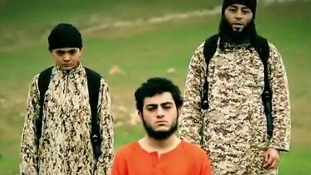 ​ISIS militants stand behind a Palestinian man identified as Muhammad Musalam before appearing to execute him 