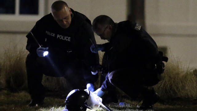 Police shine a light on a helmet as they investigate the scene where two police officers were shot outside the Ferguson Police Department March 12, 2015, in Ferguson, Mo. 