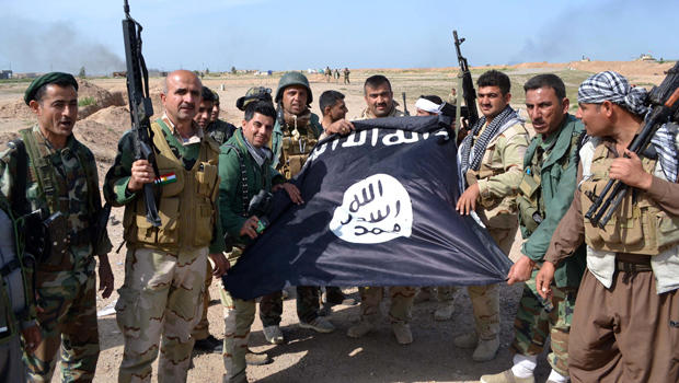 Iraqi Kurdish peshmerga fighters pose for a photo holding an Islamic State of Iraq and Syria flag in the village of Sultan Mari, west of the city of Kirkuk, March 9, 2015, after they reportedly re-took the area from ISIS jihadists. 