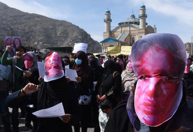 Afghan members of the Solidarity Party of Afghanistan wear masks bearing an impression of the bloodied face of Farkhunda, a woman who was lynched, during a protest against the attack in Kabul 