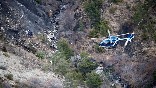 A photo released March 25, 2015, by the French Interior Ministry shows a French gendarme helicopter flying over debris at the crash site of an Airbus A320, near Seyne-les-Alpes. 
