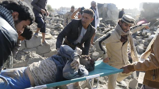 People carry the body of a man they uncovered from under the rubble of a house destroyed by an airstrike near Sanaa Airport 