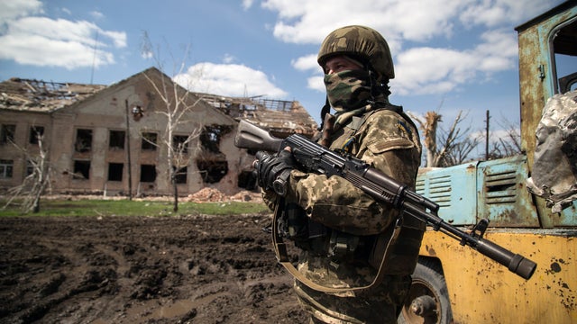 A Ukrainian serviceman stands beside a shell-damaged building in the village of Peski near Donetsk 