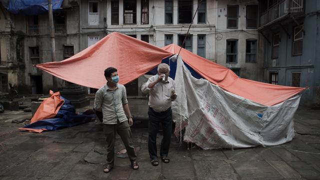 People stand outside their makeshift tent in the Nepalese capital Kathmandu on April 28, 2015, after a devastating earthquake struck the country. 