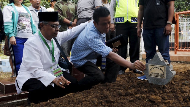 An Islamic cleric, left, consoles a relative of Indonesian death row prisoner Zaenal Abidin during his funeral in Cilacap, Central Java 