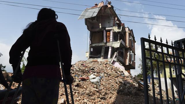 Nepalese resident Nomita Khadka leans on her crutches as she looks at the remains of her home in Kathmandu 