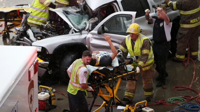 The driver of a truck which crashed during severe weather on Interstate 35 gestures to his rescuers after being cut from the truck in Moore, Okla., May 6, 2015. 