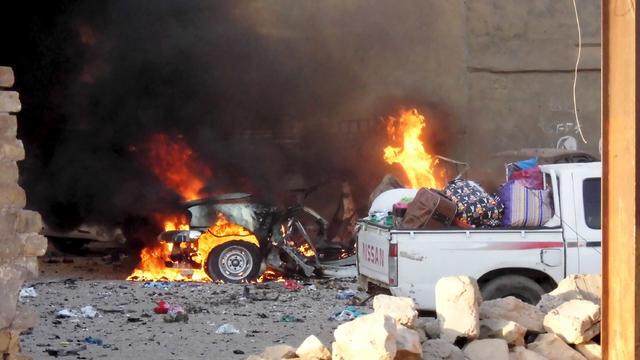 A car is engulfed by flames during clashes in the city of Ramadi 