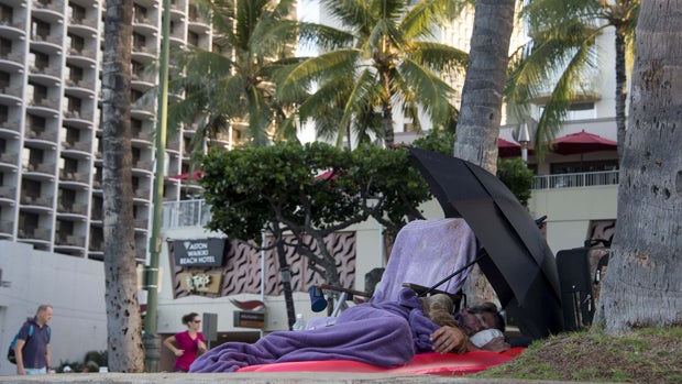 A homeless man sleeps by Waikiki Beach in Honolulu Dec. 20, 2014. 