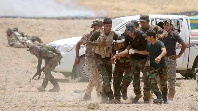 Iraqi Shiite paramilitaries help a wounded fighter after clashes with Islamist State militants in al Nibaie, in Anbar province 