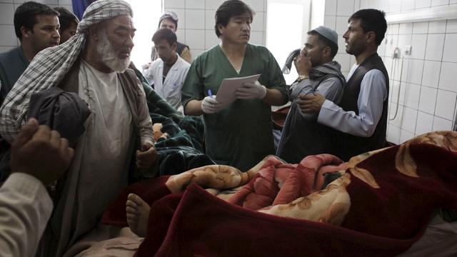 Relatives of an aid worker killed by gunmen gather around his body at a hospital in Mazar-i-Sharif 