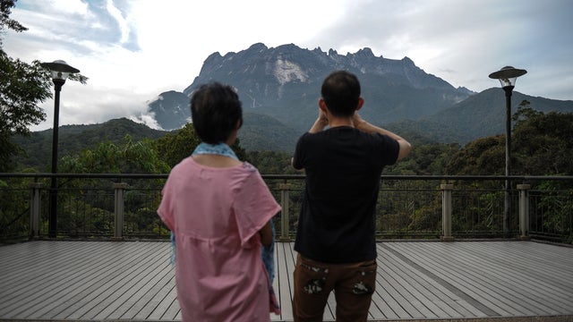 A tourist (R) takes pictures of Malaysia's Mount Kinabalu a day after the earthquake in Kundasang, a town in the district of Ranau 