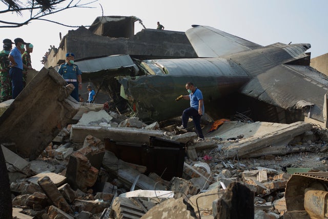 Military personnel and search and rescue teams comb through the wreckage of a military transport plane which crashed into a building