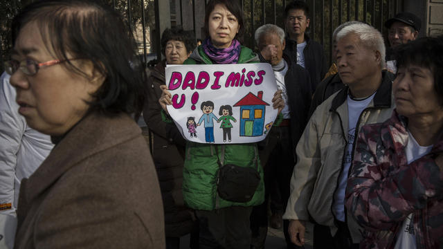 Catherine Gang whose husband is a missing passenger on Malaysia Airlines flight MH370 holds a sign as she and other relatives protest outside the Malaysia Embassy in Beijing, China 