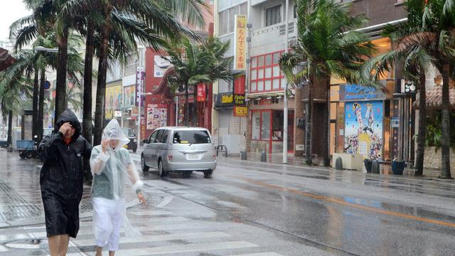 People walk on the street under heavy rain and winds caused by Typhoon Chan-hom in Naha, Okinawa Prefecture 