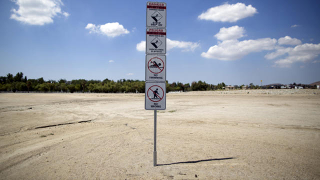 Signs warning of underwater hazards stand over a portion of dried-up lake bed at Lake Elsinore in Lake Elsinore, California, July 23, 2015. 