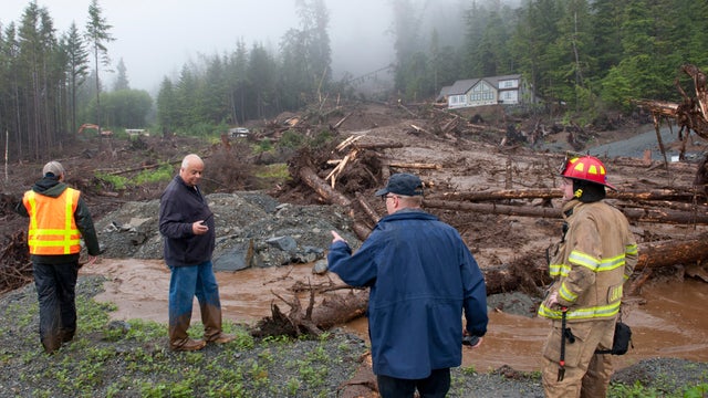 From left, city engineer Dan Tadic, Fire Chief Dave Miller, Search and Rescue Capt. Lance Ewers and firefighter Rob Janik look at the damage caused by a landslide Aug. 18, 2015, in Sitka, Alaska. 
