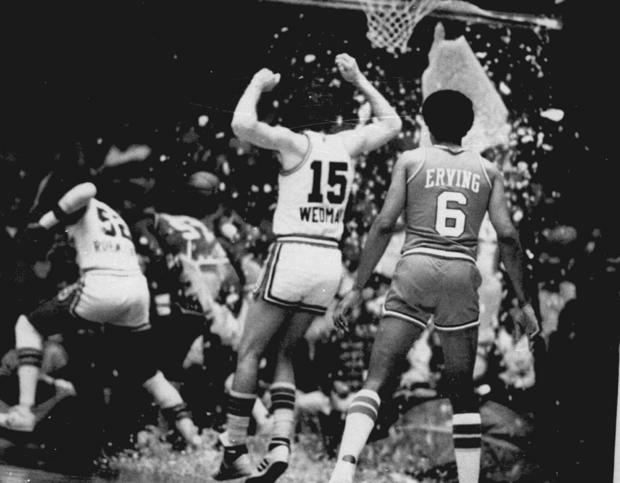 This November 1979 file photo shows Kansas City Kings' Scott Wedman and Philadelphia 76ers' Julius Erving watching as Kings' Bill Robinzine, left, and 76ers' Darryl Dawkins run for cover after Dawkins shattered the glass backboard during a basketball game 