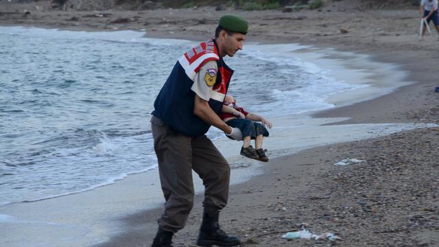 A Turkish gendarmerie carries the body of Aylan Kurdi, a Syrian boy who drowned in his family's failed attempt to sail to the Greek island of Kos 