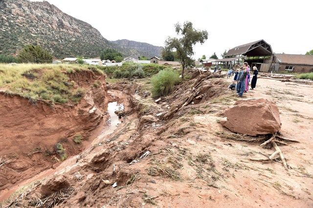 Residents look down on estimated 50-foot deep gorge created when flash flood hit Hildale, Utah on September 15, 2015 