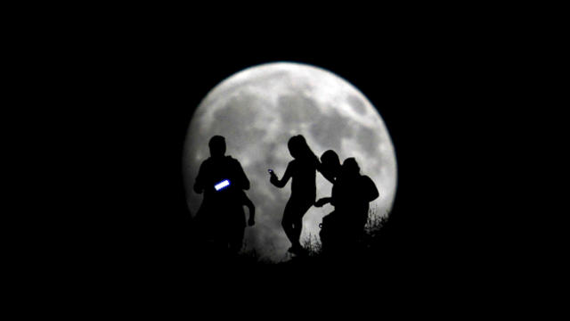 A group of hikers are seen silhouetted against the moon in Tijuana, Mexico, Aug. 27, 2015. 