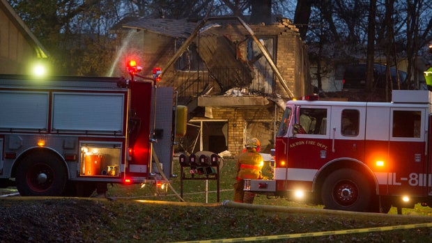 Firefighters work at the scene where authorities say a small business jet crashed into an apartment building in Akron, Ohio, Nov. 10, 2015. 