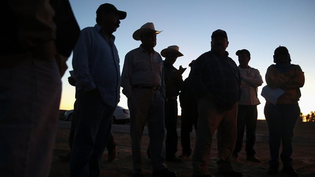 Mexican agricultural workers stand in the pre-dawn chill before starting work Oct. 8, 2013, in Holtville, California. Thousands of Mexican workers cross the border legally each night from Mexicali, Mexico, into Calexico, California, where they pick up wor 