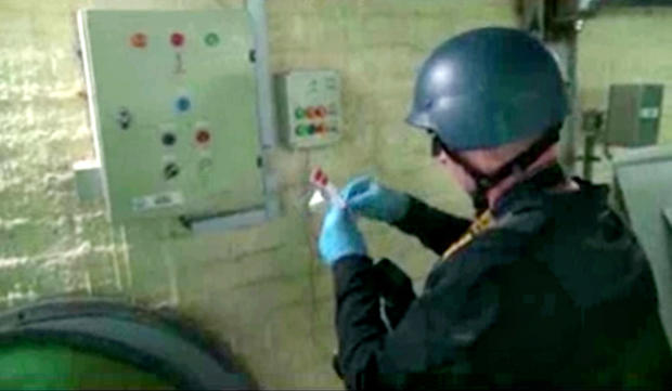 This file image made from video broadcast on Syrian State Television on Oct. 8, 2013, purports to show a chemical weapons expert taking samples at a chemical weapons plant at an unknown location in Syria. 