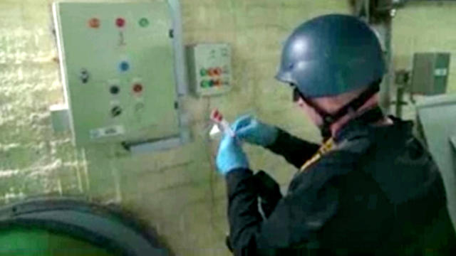 This file image made from video broadcast on Syrian State Television on Oct. 8, 2013, purports to show a chemical weapons expert taking samples at a chemical weapons plant at an unknown location in Syria. 