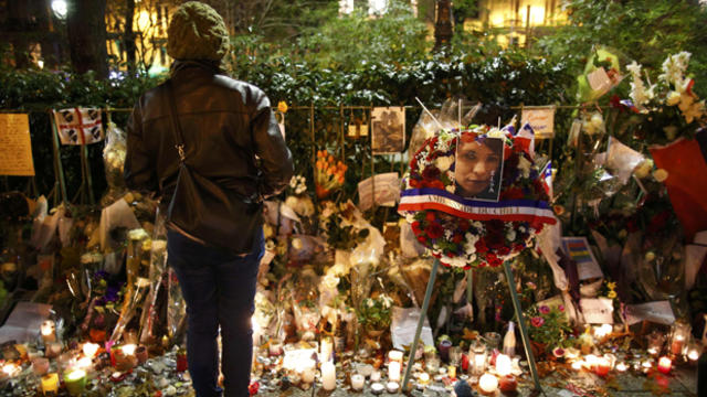 A woman looks at flowers, candles and messages in tribute to victims of the Paris terror attacks near the Bataclan concert hall, one of the sites of the attacks in Paris, France, Nov. 20, 2015. 