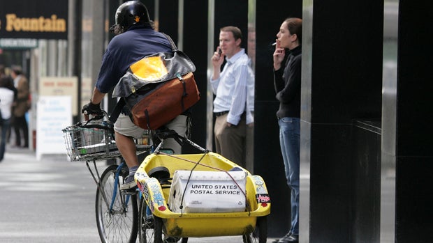 A bike messenger rides past people taking a break near an office building July 17, 2007, in San Francisco, California. 