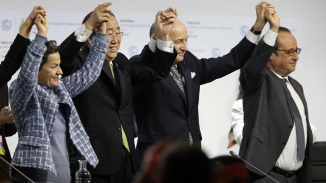 Laurent Fabius, center, French foreign affairs minister and president-designate of COP21, raises hands with U.N. Secretary-General Ban Ki-moon, second left, and France's President Francois Hollande, right, after the adoption of a historic global warming p 