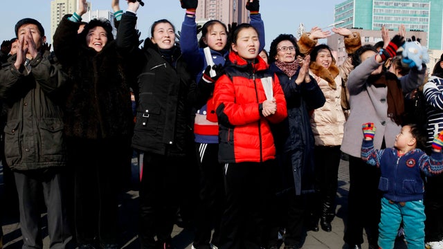 North Koreans react as they watch a news broadcast on a video screen outside Pyongyang Railway Station in Pyongyang 