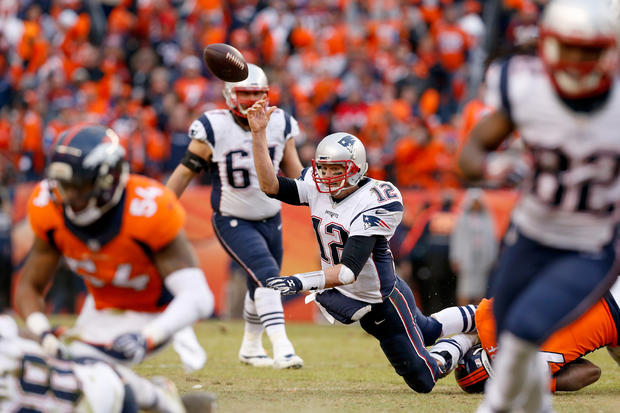 Tom Brady gets hit as he throws. 