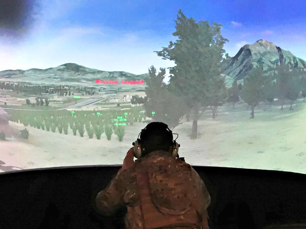 U.S. Air Force Staff Sgt. Bobby McDonald sits in front of a large screen depicting a simulated battle field, to practice calling in precision airstrikes during joint U.S.-Latvian military exercises at a base in Ādaži, Latvia 