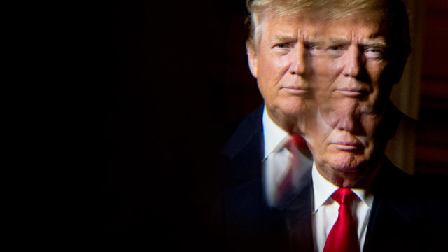 Donald Trump, seen in reflection, poses for a portrait following an interview with The Associated Press at the Trump National Golf Club in Sterling, Virginia, Dec. 2, 2015. 