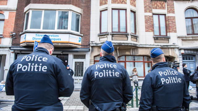Three police officers stand guard at the Meiser neighborhood in Schaerbeek in Brussels on March 25, 2016, during an anti-terrorist operation searching for suspects of the Brussels terrorist attacks. 
