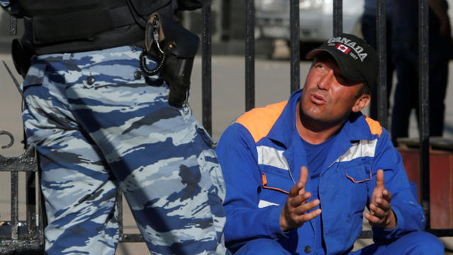 ​A man who was detained following a mass brawl addresses an Interior Ministry officer near the Khovanskoye cemetery in southwest Moscow, Russia, May 14, 2016. 