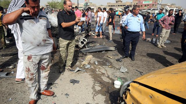 Iraqi civilians and security forces check the damage after a suicide bomber detonated an explosives-rigged vehicle in northern Baghdad's Sadr City 