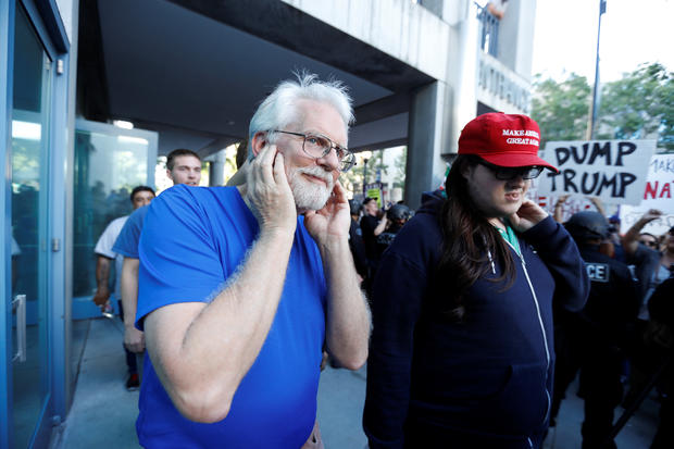 Donald Trump supporter covers his ears as he walks past demonstrator outside Trump rally in San Jose, California, on June 2, 2016 