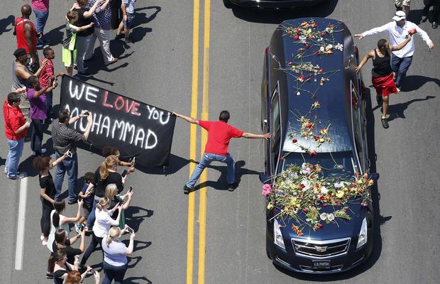 A well-wisher holding a banner touches the hearse carrying the remains of Muhammad Ali during the funeral procession for the three-time heavyweight boxing champion in Louisville, Kentucky, June 10, 2016. 