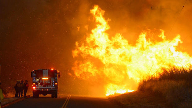 ​Firefighters from the Lompoc City Fire Department take shelter behind their engine June 16, 2016, as wind-driven flames advance from the Sherpa Fire. The flames were crossing Calle Real near El Capitan State Park in Santa Barbara County, California. 