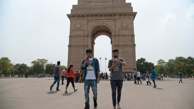 Shivanu Mandal, left, and Geet Singh look at their screens as they play "Pokemon Go" in front of the landmark India Gate monument in New Delhi, India, Friday, July 22, 2016. 